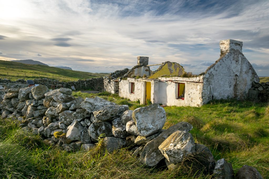 only the walls and a stone fence remain standing from the old Irish farmhouse